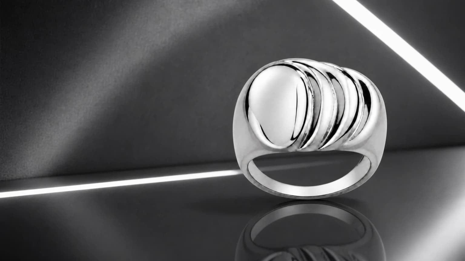 Wide sculpted silver ring on a graphite mirrored set